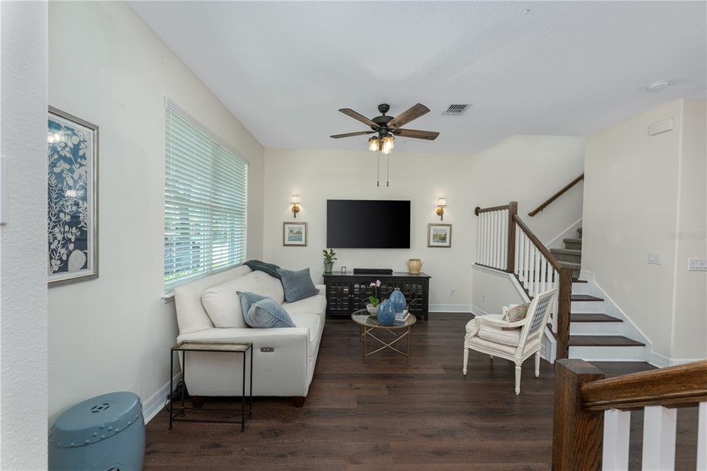 A living room with dark wood floors, a white sofa, a television, and a staircase — 453 GEE HAMMOCK LANE, WINTER SPRINGS, FL