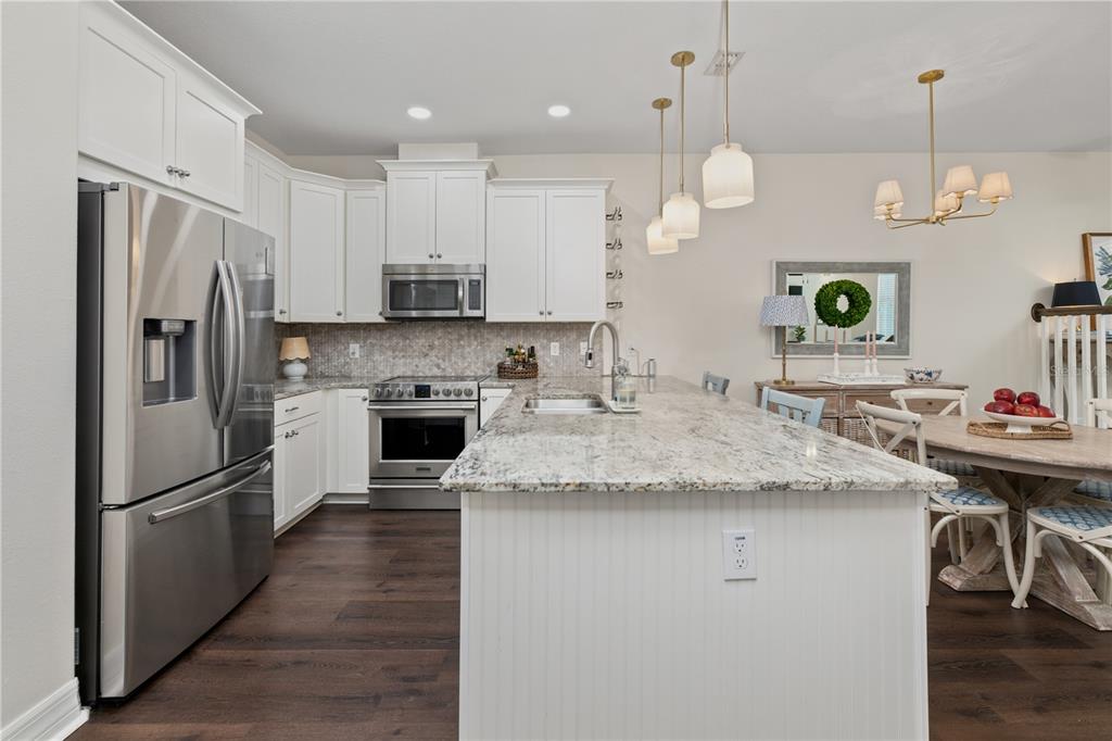 A kitchen features white cabinets, granite countertops, stainless steel appliances, and an island with seating — 453 GEE HAMMOCK LANE, WINTER SPRINGS, FL