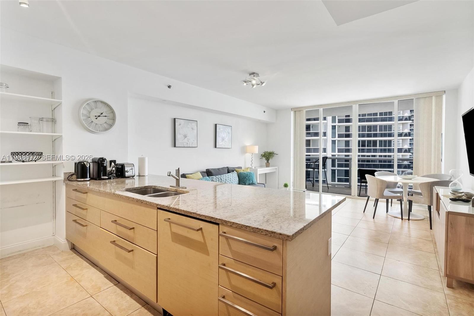 A kitchen island with granite countertops sits in an open-concept living area with tile floors — 1830 S Ocean Dr # 2409, Hallandale Beach FL 33009, HALLANDALE BEACH, FL