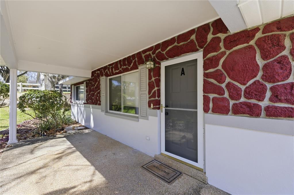A covered concrete porch leads to a front door with a red stone facade — 8637 SW 97TH LANE ROAD UNIT A, OCALA, FL