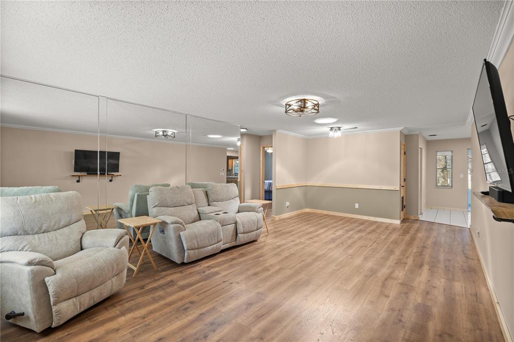 A living room features light wood-look flooring, beige walls, mirrored panels, and two reclining chairs — 8637 SW 97TH LANE ROAD UNIT A, OCALA, FL