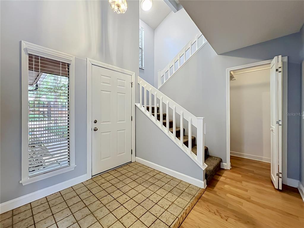 An entryway features a tiled floor, a white front door, and a carpeted staircase — 125 RAINTREE DRIVE, LONGWOOD, FL