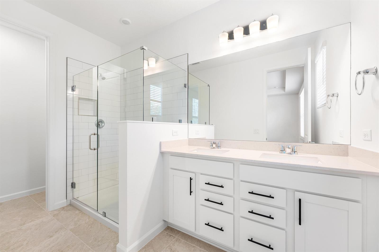 A bright bathroom features a glass-enclosed shower, double vanity with white cabinets, and large mirror — 4333 Efendi Drive, Lantana FL 33462, LANTANA, FL