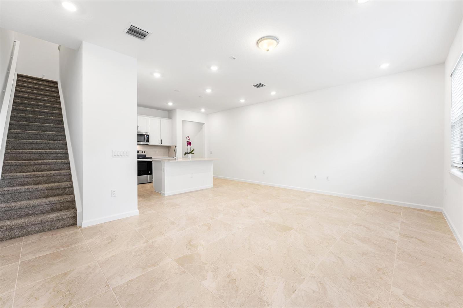 An open-concept living area features a kitchen with white cabinets and beige tile flooring — 4333 Efendi Drive, Lantana FL 33462, LANTANA, FL