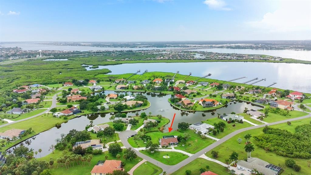 An aerial view shows a house with a pool situated on a lakefront lot — 6187 9TH AVENUE CIRCLE NE, BRADENTON, FL
