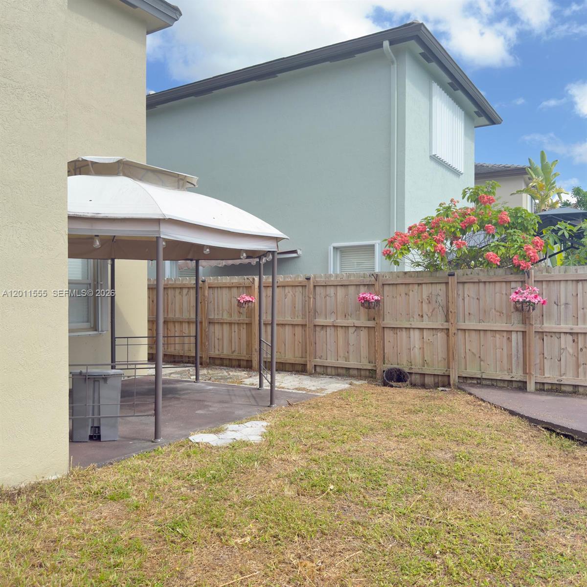 A backyard features a gazebo on a concrete patio, a wooden fence, and landscaping — 148 NE 36 Ave RD, Homestead FL 33033, HOMESTEAD, FL
