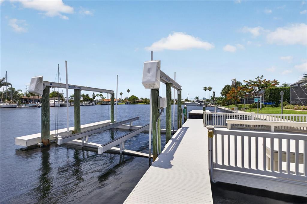A boat lift sits beside a white wooden dock extending into a canal — 3640 HARBORVIEW COURT, NEW PORT RICHEY, FL