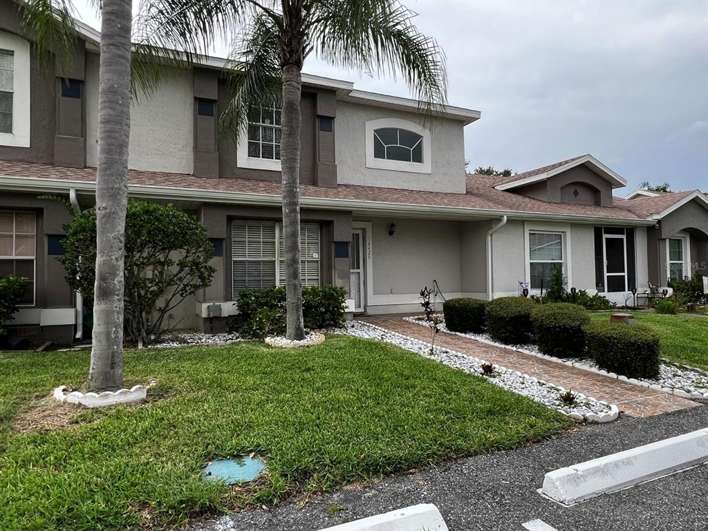 A two-story townhouse with a palm tree, a brick walkway, and a small front lawn — 14426 ISLAND COVE DRIVE, ORLANDO, FL