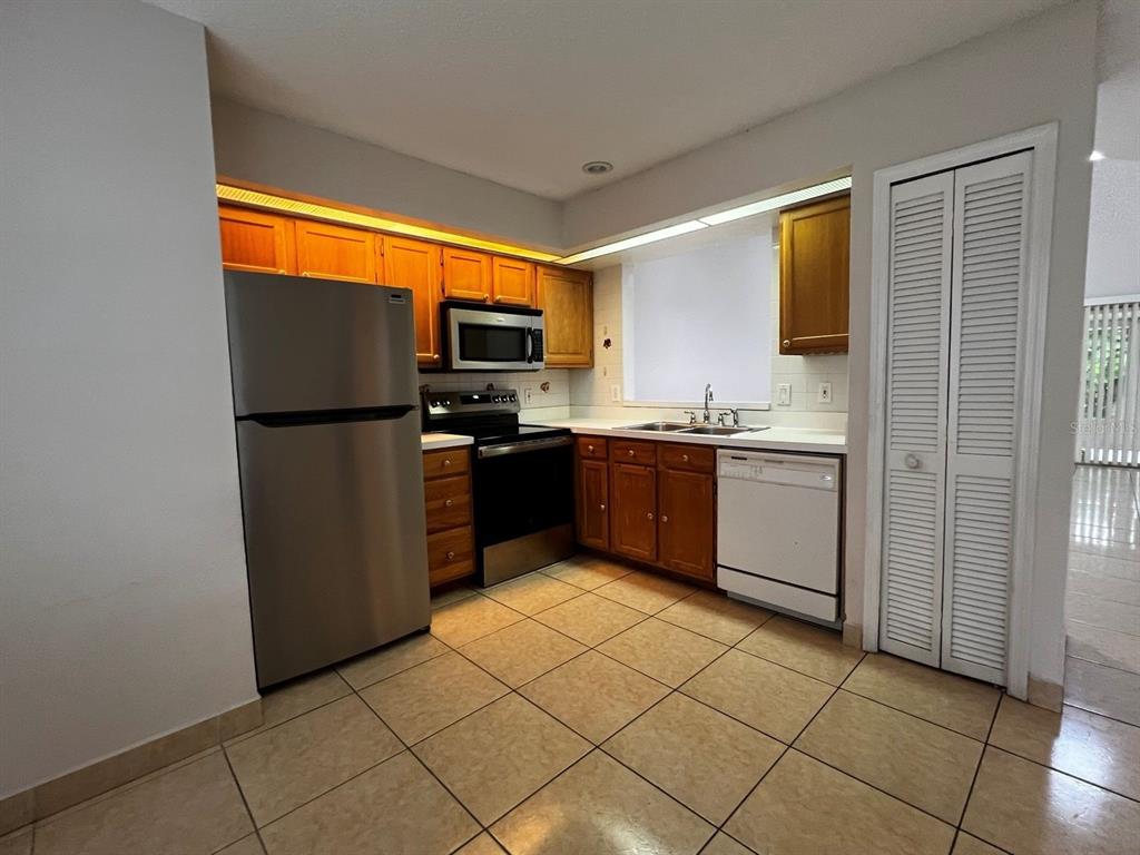 A kitchen with wood cabinets, stainless steel appliances, and beige tile flooring — 14426 ISLAND COVE DRIVE, ORLANDO, FL
