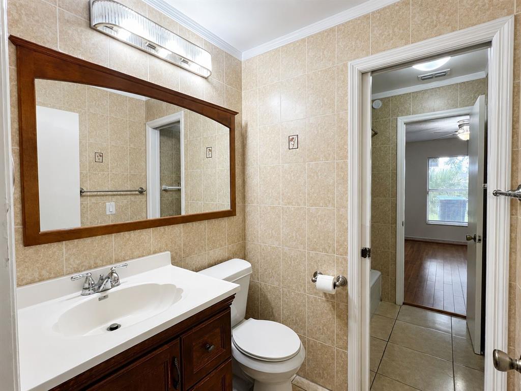 A bathroom features a wood vanity, a framed mirror, and beige tiled walls and floors — 14426 ISLAND COVE DRIVE, ORLANDO, FL