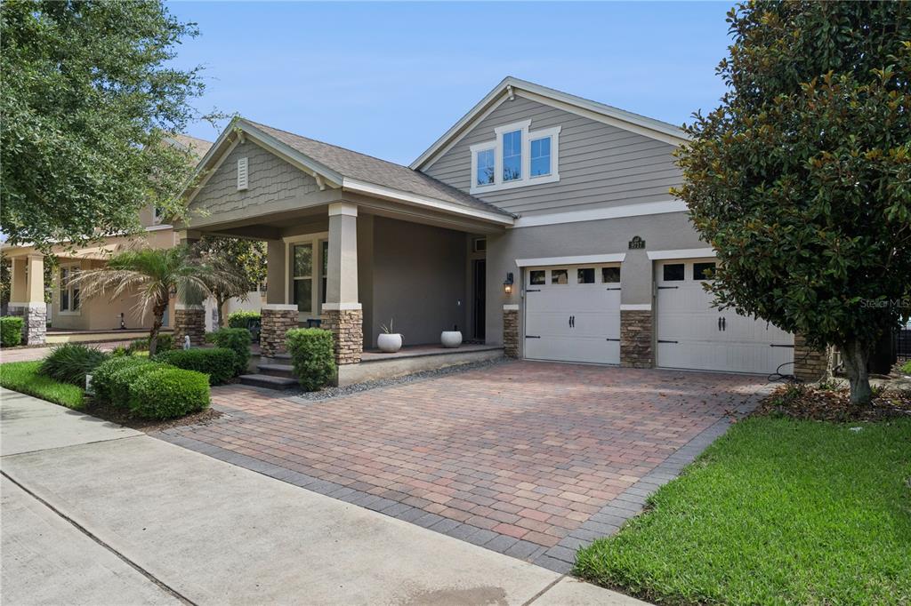 A single-story house with a stone-accented porch, a brick paver driveway, and a two-car garage — 9717 WATERWAY PASSAGE DRIVE, WINTER GARDEN, FL