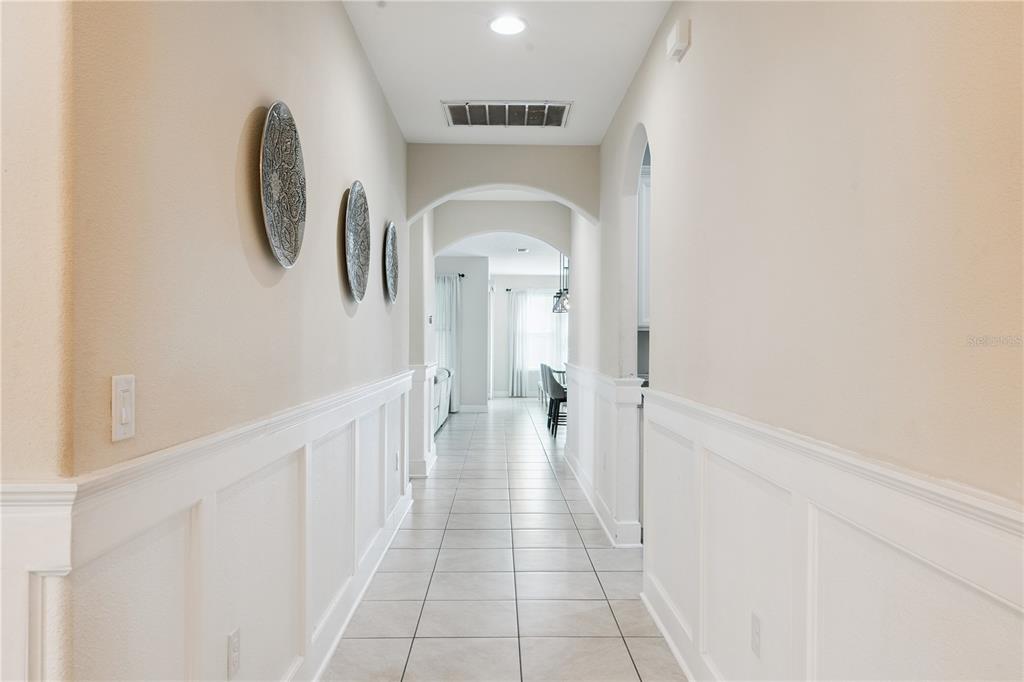 A long hallway features white wainscoting, tile flooring, and three decorative plates on the wall — 9717 WATERWAY PASSAGE DRIVE, WINTER GARDEN, FL
