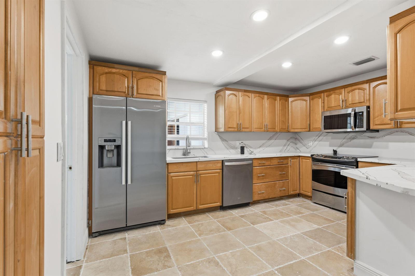 A kitchen with wood cabinets, stainless steel appliances, and white countertops with gray veining — 4793 Badger Avenue, West Palm Beach FL 33417, WEST PALM BEACH, FL