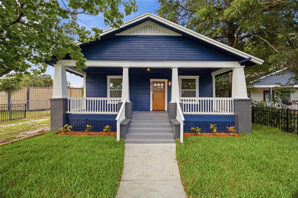 A blue bungalow with a front porch, white columns, and a wooden front door — 815 E FRIERSON AVENUE, TAMPA, FL