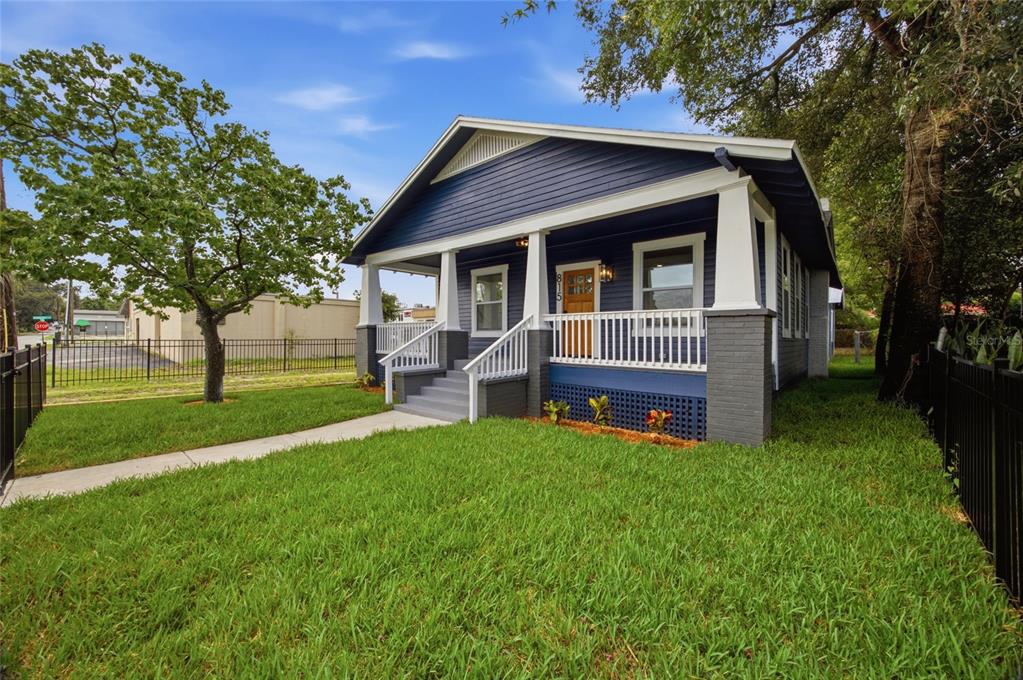 A blue bungalow with a front porch, white columns, and a gray brick foundation — 815 E FRIERSON AVENUE, TAMPA, FL