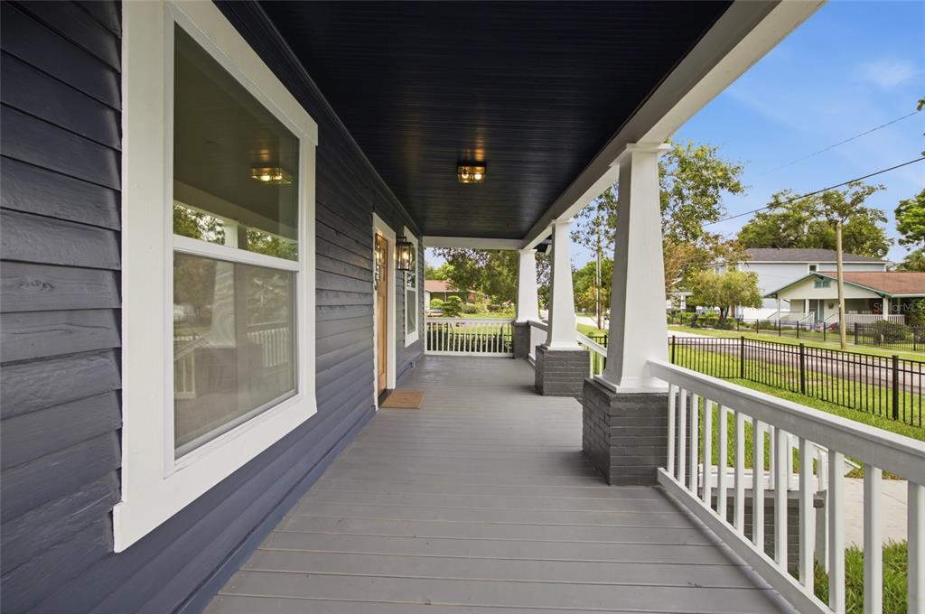 A covered front porch with dark blue siding, white railings, and white columns — 815 E FRIERSON AVENUE, TAMPA, FL