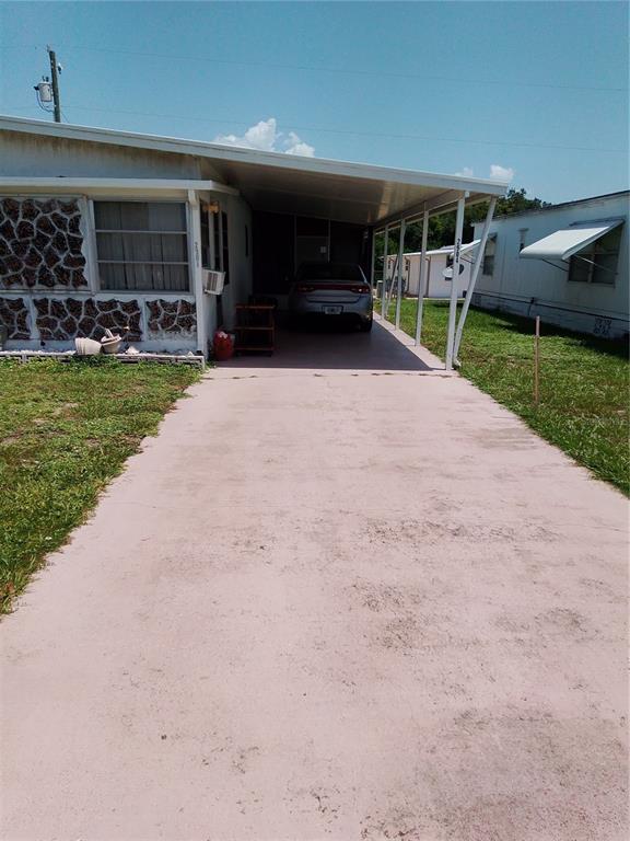 A mobile home exterior features a painted concrete driveway and a covered carport with a car — 2904 LAS VEGAS BOULEVARD, SEBRING, FL
