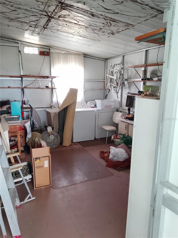 A cluttered utility room features a washer, dryer, shelving units, and a window with curtains — 2904 LAS VEGAS BOULEVARD, SEBRING, FL
