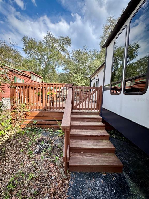 A wooden staircase leads to a deck with a railing beside a mobile home — 25132 NE 143RD STREET UNIT 52, FORT MC COY, FL