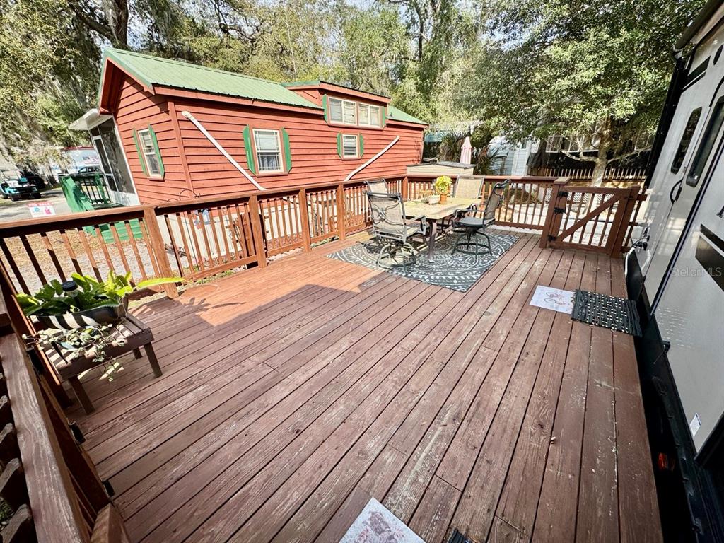 A wooden deck features a dining set, a small plant stand, and a red cabin — 25132 NE 143RD STREET UNIT 52, FORT MC COY, FL