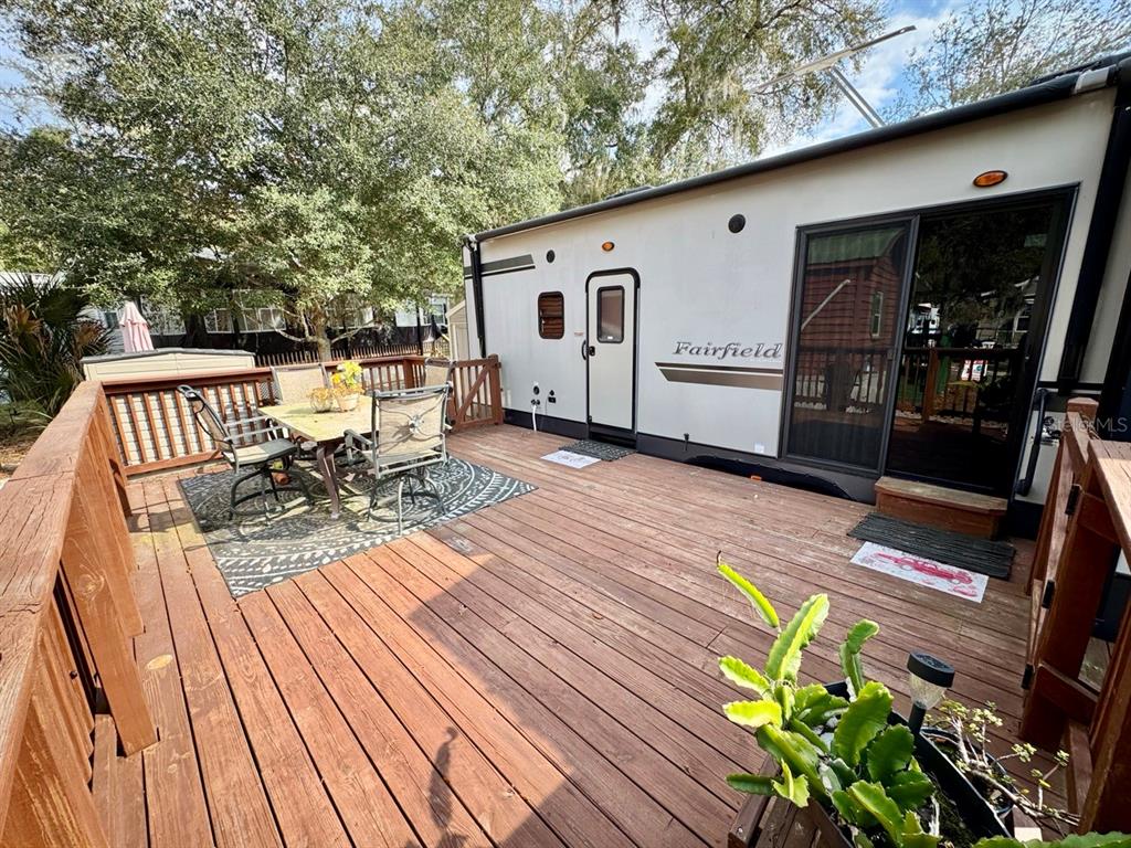 A wooden deck features a dining set and a parked recreational vehicle with sliding doors — 25132 NE 143RD STREET UNIT 52, FORT MC COY, FL