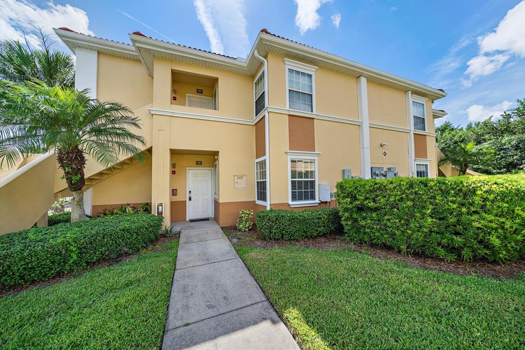 A two-story tan apartment building with a concrete walkway and a palm tree — 1010 VILLAGIO CIRCLE UNIT 104, SARASOTA, FL