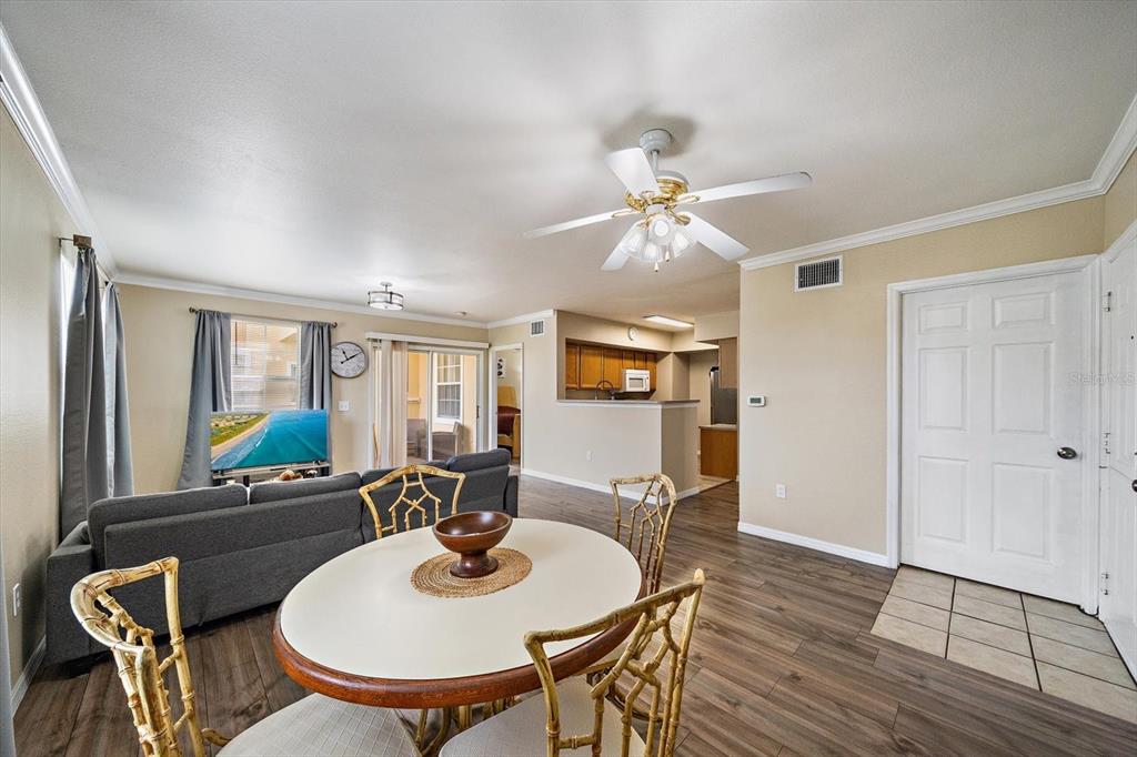 A living and dining area with wood-look flooring, a ceiling fan, and an open kitchen — 1010 VILLAGIO CIRCLE UNIT 104, SARASOTA, FL