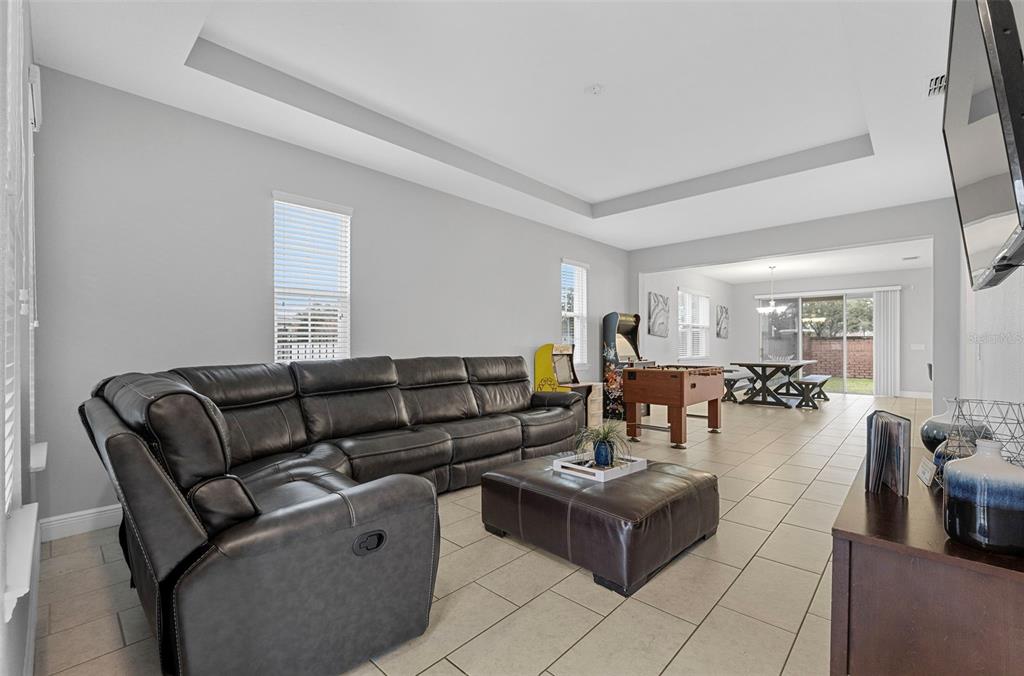 A spacious living room features a large gray sectional, a leather ottoman, and a game area — 206 ABERDEEN ST, DAVENPORT, FL