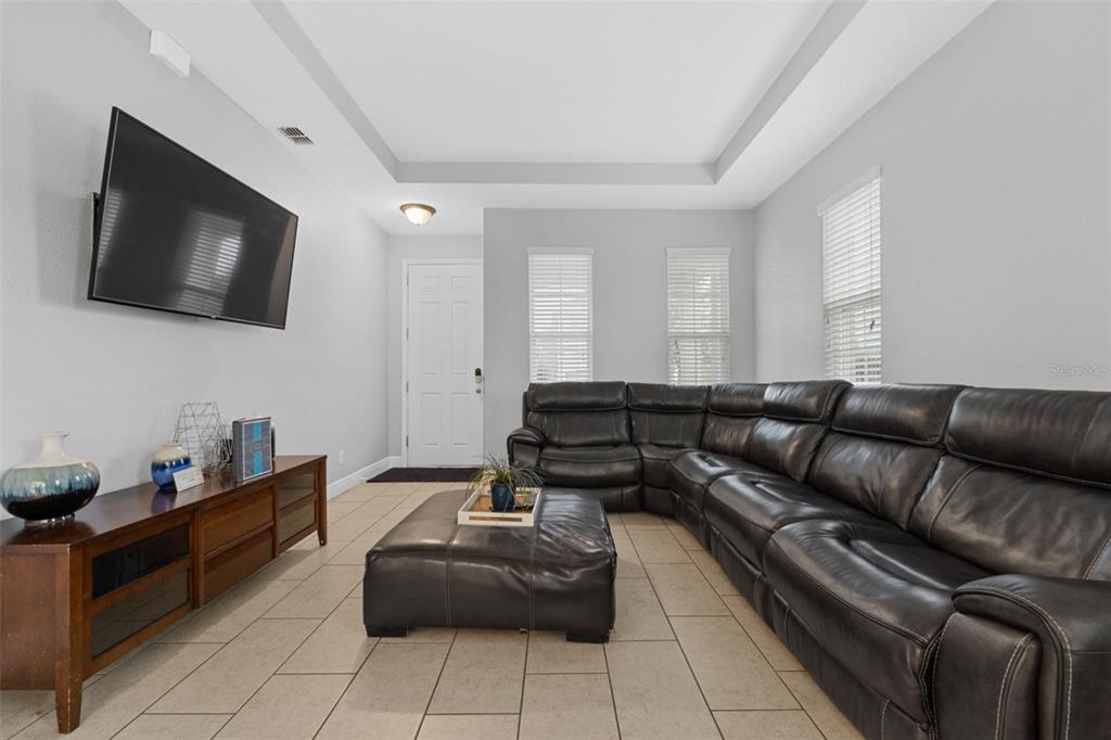 A living room features a large dark leather sectional, a matching ottoman, and a wall-mounted television — 206 ABERDEEN ST, DAVENPORT, FL