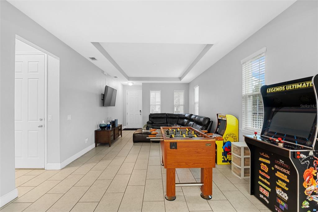 A game room features tile flooring, a foosball table, arcade cabinets, and a sectional sofa — 206 ABERDEEN ST, DAVENPORT, FL