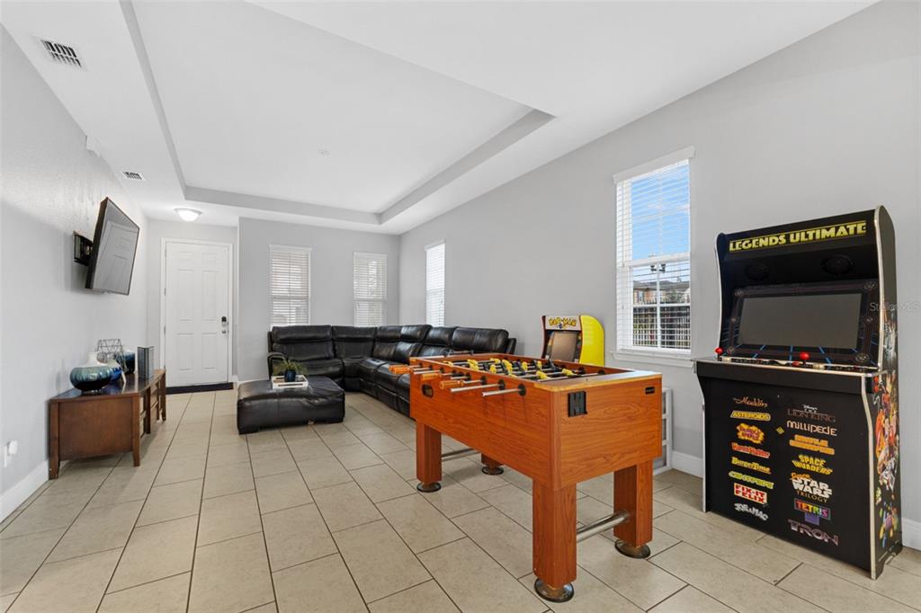 A game room features a foosball table, an arcade cabinet, a sectional sofa, and tile flooring — 206 ABERDEEN ST, DAVENPORT, FL