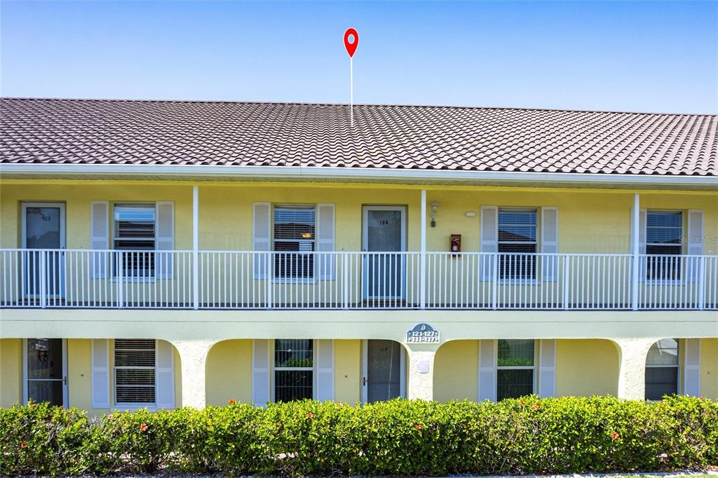 A two-story yellow apartment building features white railings, shuttered windows, and a tiled roof — 4000 BAL HARBOR BOULEVARD UNIT 124, PUNTA GORDA, FL