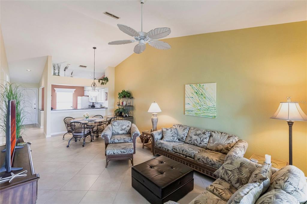 A living room with vaulted ceilings, tile floors, a ceiling fan, and a dining area — 4000 BAL HARBOR BOULEVARD UNIT 124, PUNTA GORDA, FL