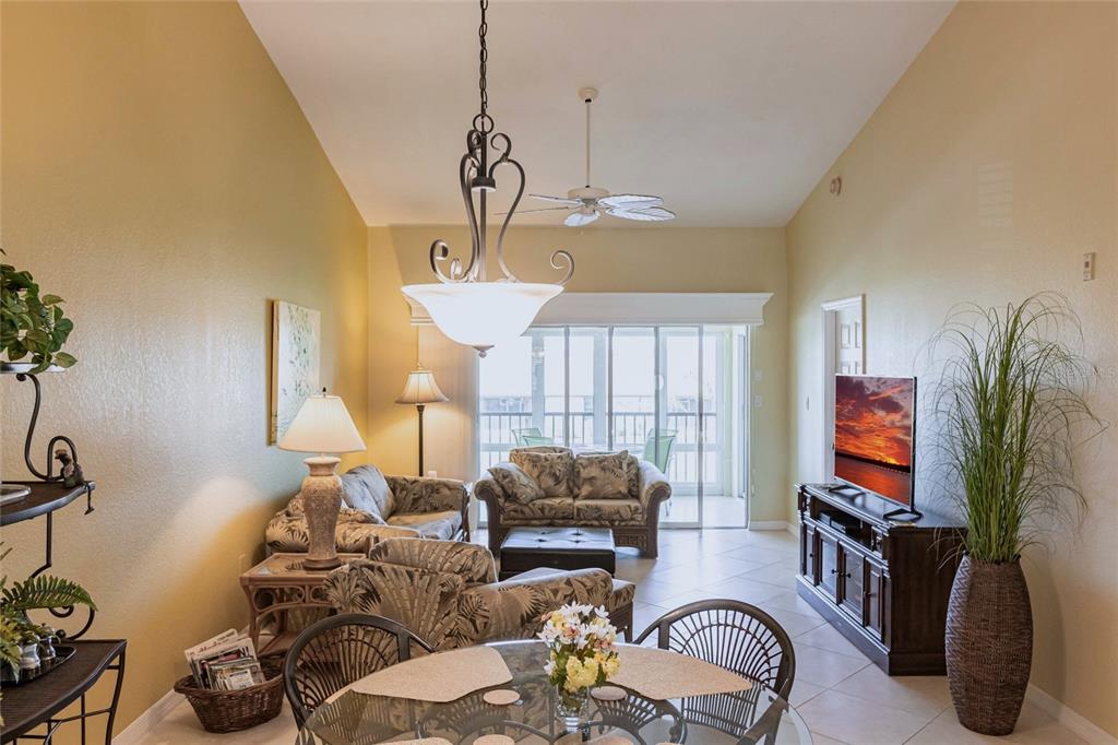 A living room with vaulted ceilings, tile floors, a ceiling fan, and a sliding glass door — 4000 BAL HARBOR BOULEVARD UNIT 124, PUNTA GORDA, FL