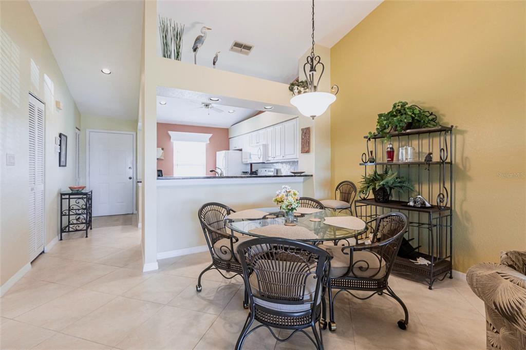 A dining area with a glass table, wicker chairs, and an open view into the kitchen — 4000 BAL HARBOR BOULEVARD UNIT 124, PUNTA GORDA, FL