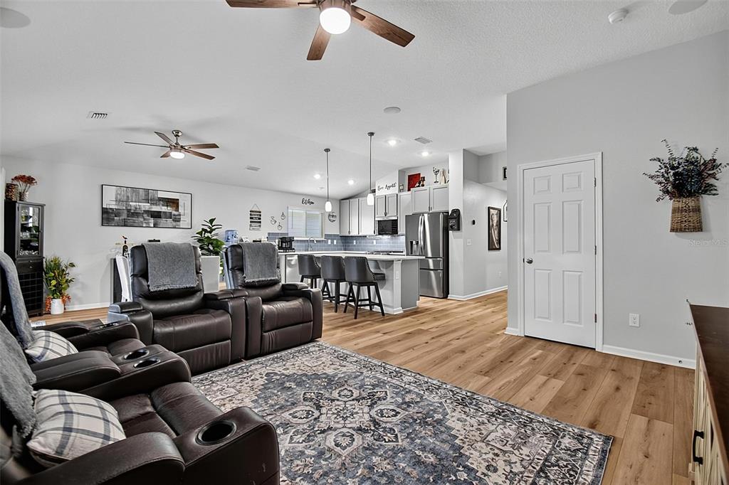 An open-concept living room and kitchen featuring leather recliners, wood-look flooring, and a center island — 7 SIGNET COURT, FLAGLER BEACH, FL