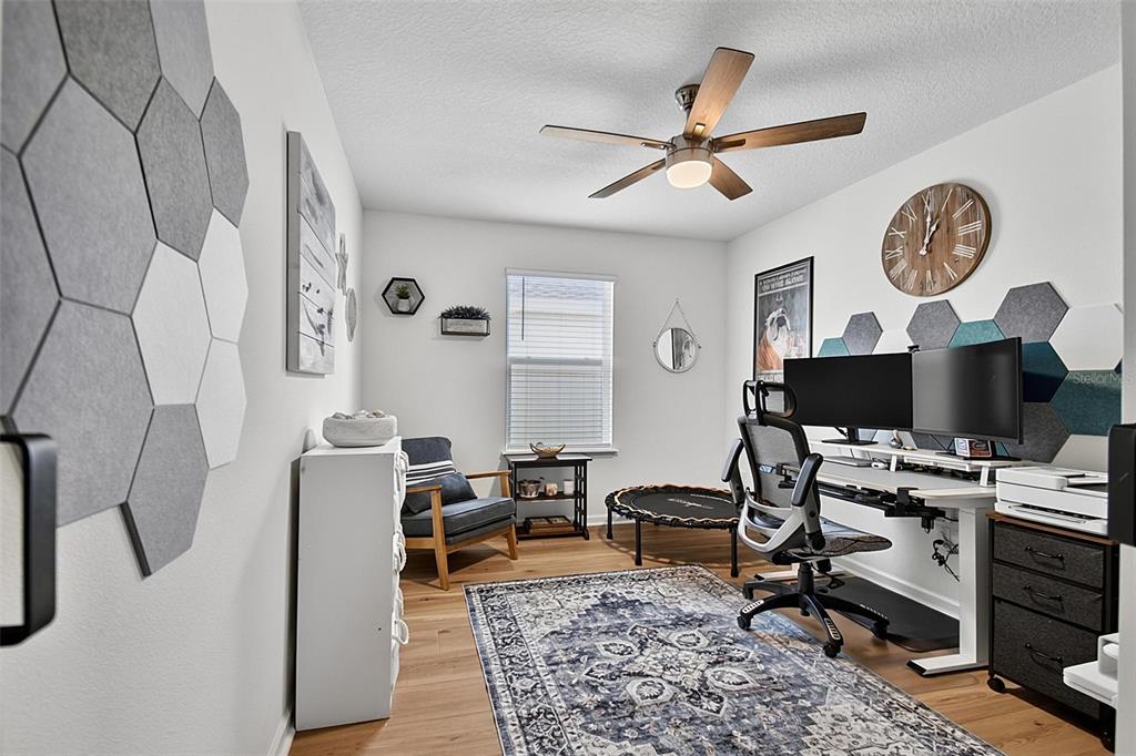 A home office features a desk with dual monitors, a rug, and hexagonal wall panels — 7 SIGNET COURT, FLAGLER BEACH, FL