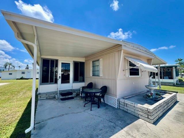 A mobile home exterior features a covered carport, a small patio, and a stone planter — 10818 FREEDOM DRIVE, PORT RICHEY, FL