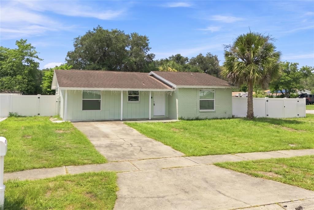 A light green, single-story house with a concrete driveway and a white vinyl fence — 8344 DRYCREEK DRIVE, TAMPA, FL