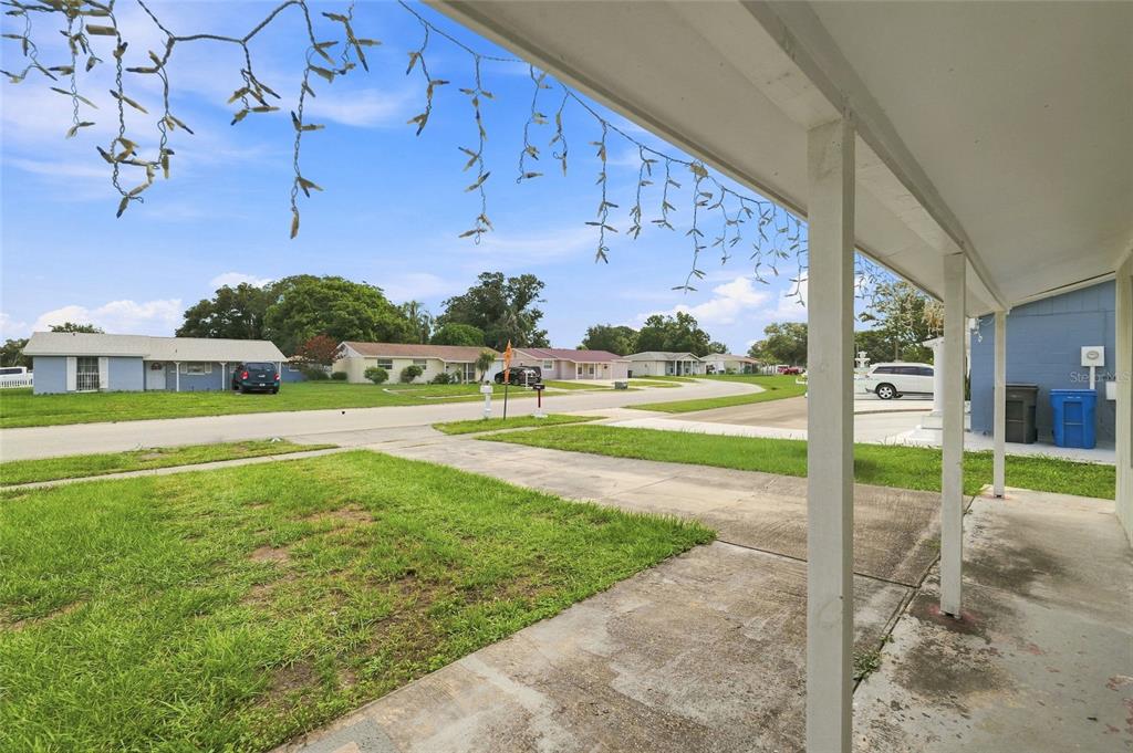 A view from a covered porch looking out over a suburban street and neighboring houses — 8344 DRYCREEK DRIVE, TAMPA, FL