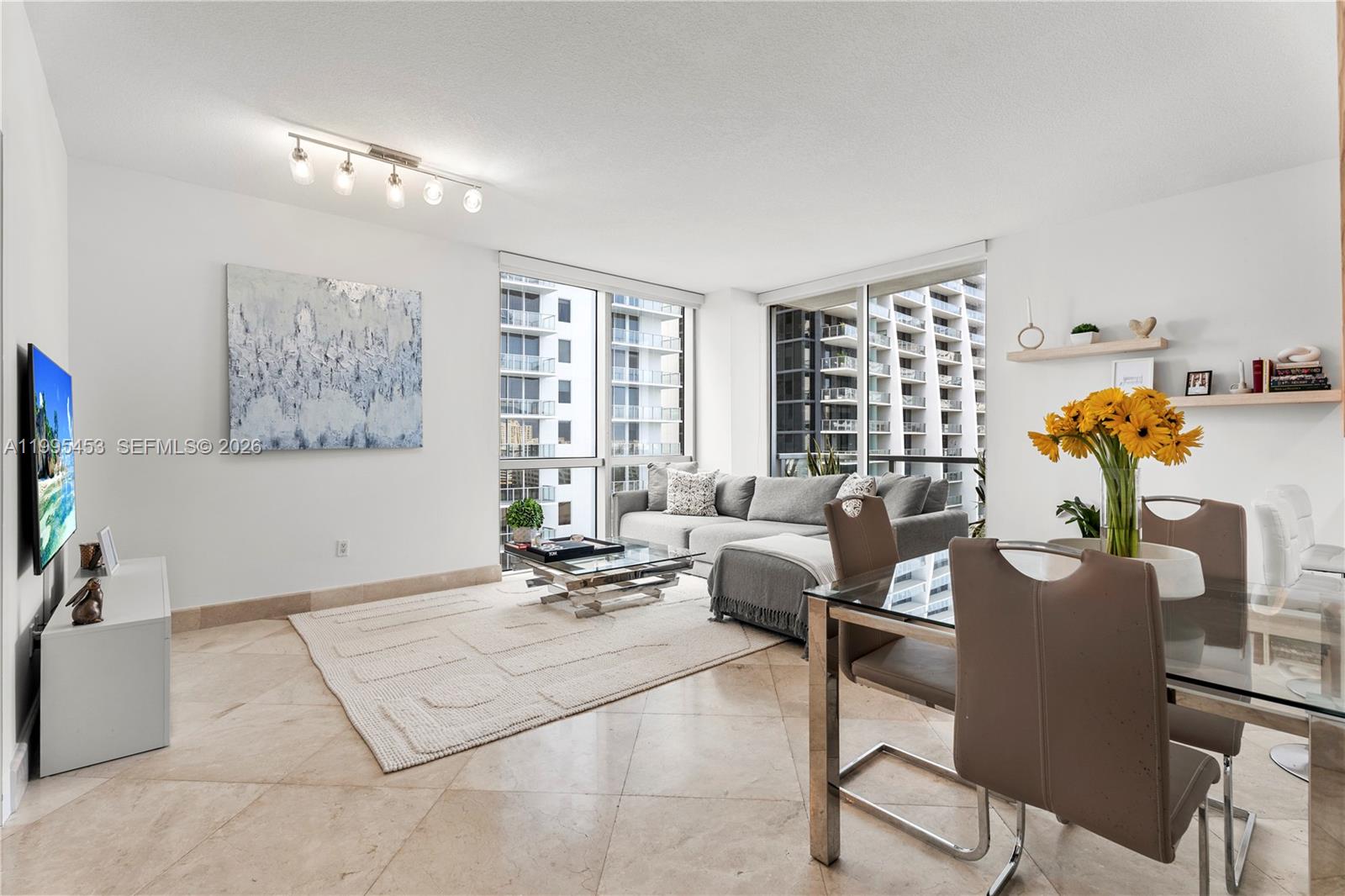 A living and dining area features tile floors, a gray sectional, and floor-to-ceiling windows — 1060 Brickell Ave # 2117, Miami FL 33131, MIAMI, FL