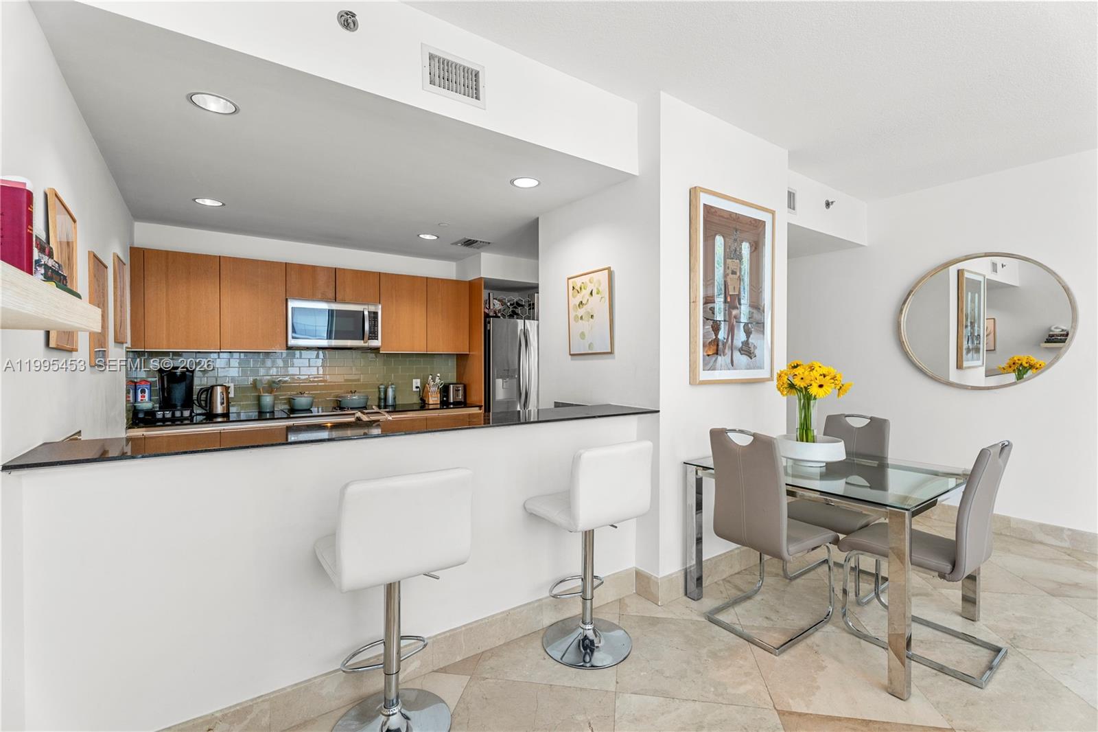 A kitchen with wood cabinets and a breakfast bar sits next to a dining area — 1060 Brickell Ave # 2117, Miami FL 33131, MIAMI, FL