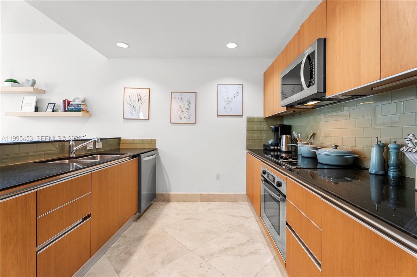 A galley kitchen features light wood cabinets, black countertops, and a green tile backsplash — 1060 Brickell Ave # 2117, Miami FL 33131, MIAMI, FL