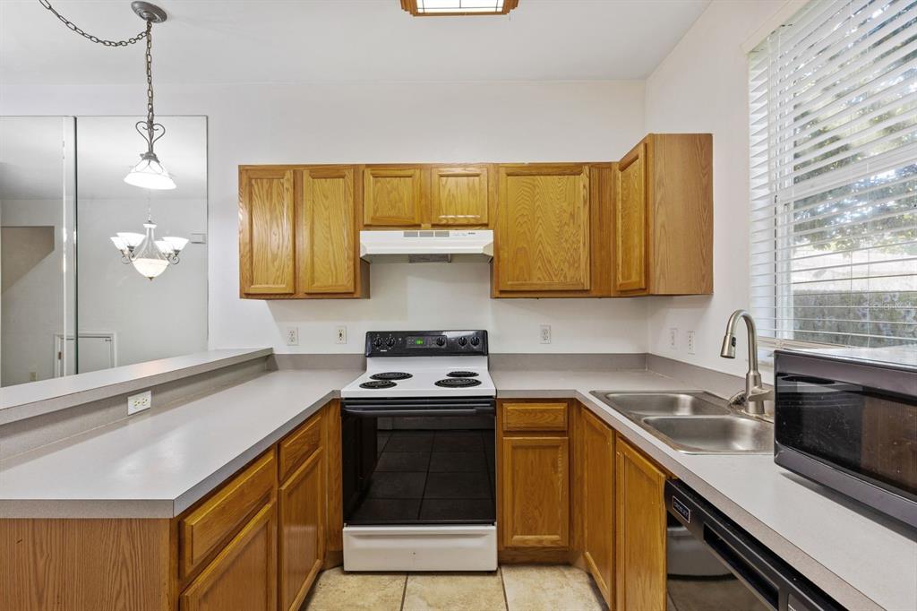 A kitchen features oak cabinets, white appliances, gray countertops, and a double-basin stainless steel sink — 3552 SW 30TH WAY UNIT 138, GAINESVILLE, FL
