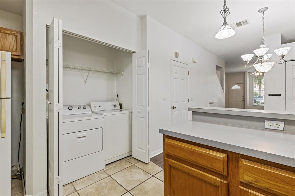 A laundry closet with a washer and dryer sits next to a kitchen counter — 3552 SW 30TH WAY UNIT 138, GAINESVILLE, FL