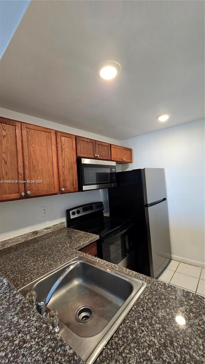 A kitchen features wood cabinets, granite countertops, a stainless steel sink, and black appliances — 498 NW 165th St Rd # 407, Miami FL 33169, MIAMI, FL