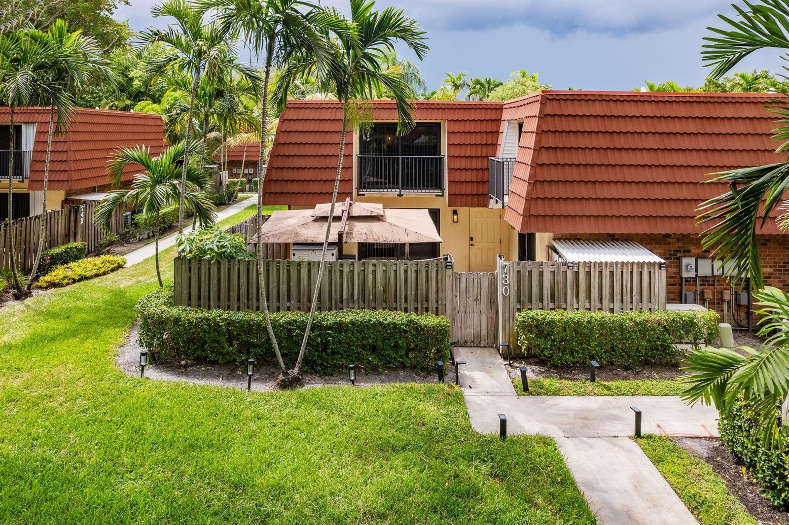An exterior view of a two-story townhouse with a red tile roof and fenced patio — 730 NW 99th Circle, Plantation FL 33324, PLANTATION, FL