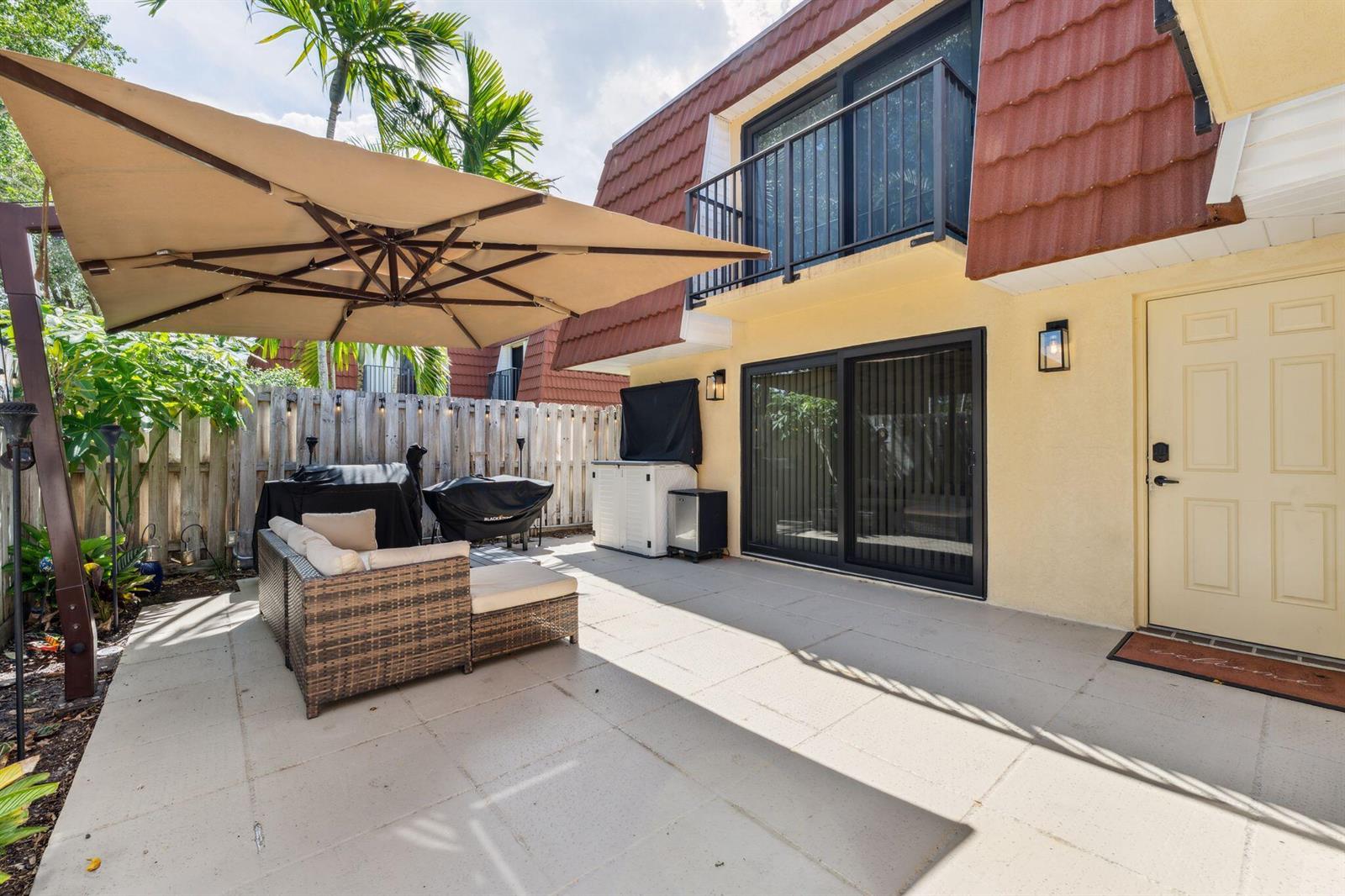 A patio features a large umbrella, wicker furniture, a grill, and a sliding glass door — 730 NW 99th Circle, Plantation FL 33324, PLANTATION, FL