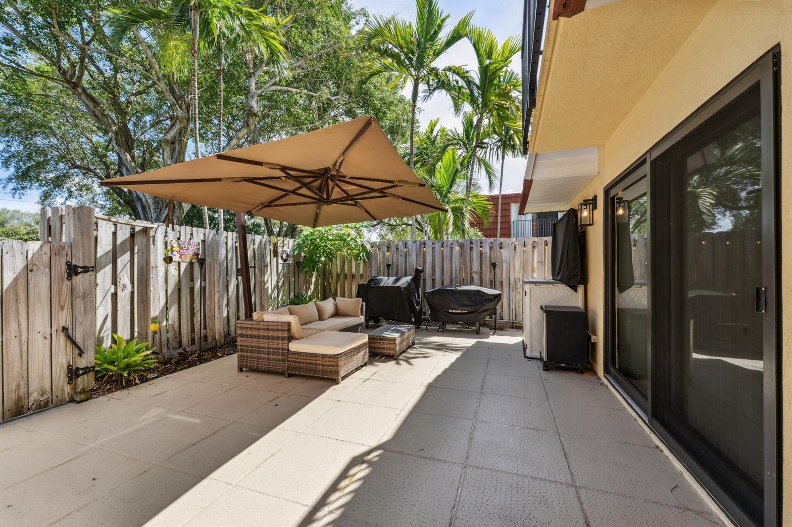 A paved patio features a sectional sofa, a large umbrella, and two covered grills — 730 NW 99th Circle, Plantation FL 33324, PLANTATION, FL