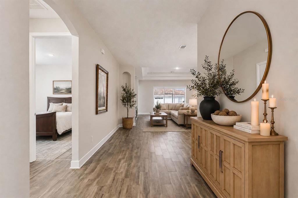 A hallway with wood-look tile flooring leads to a living room with a sofa — 523 BELLISSIMO PLACE, HOWEY IN THE HILLS, FL